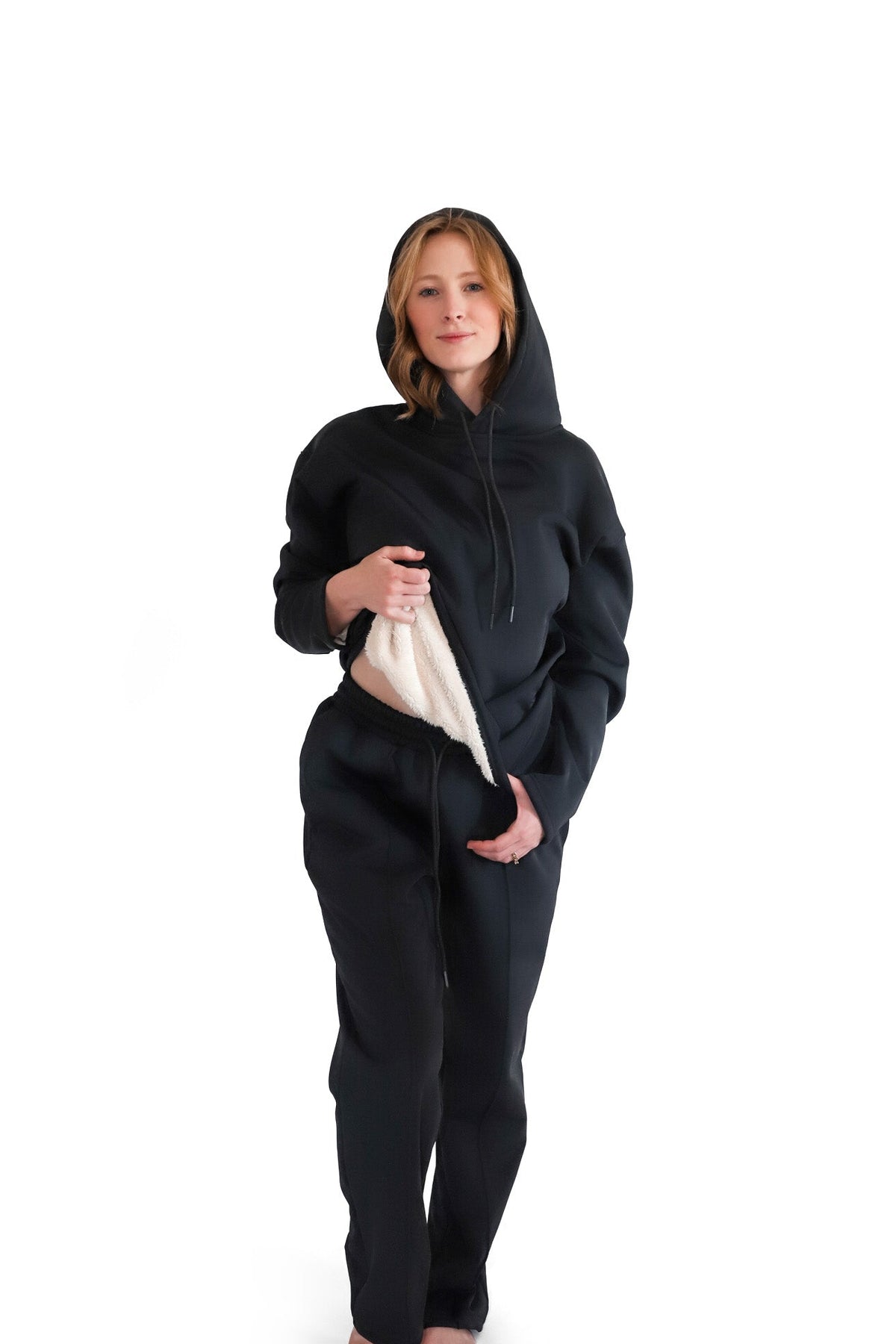 Woman lifting hem of LUU pet hair resistant hoodie to show sweatpants waistband in black