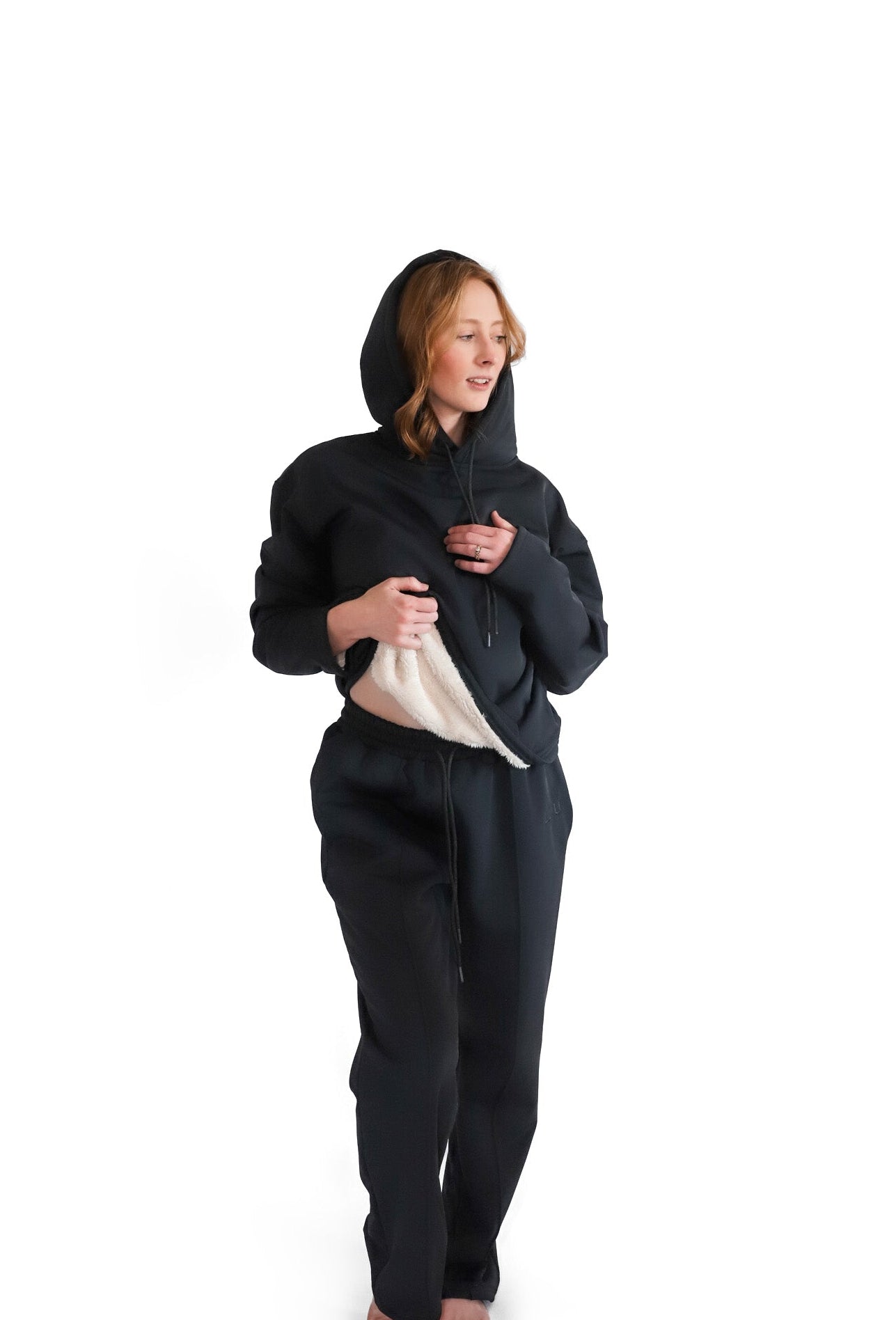 A person wearing a black hoodie with a hood, standing against a white background.