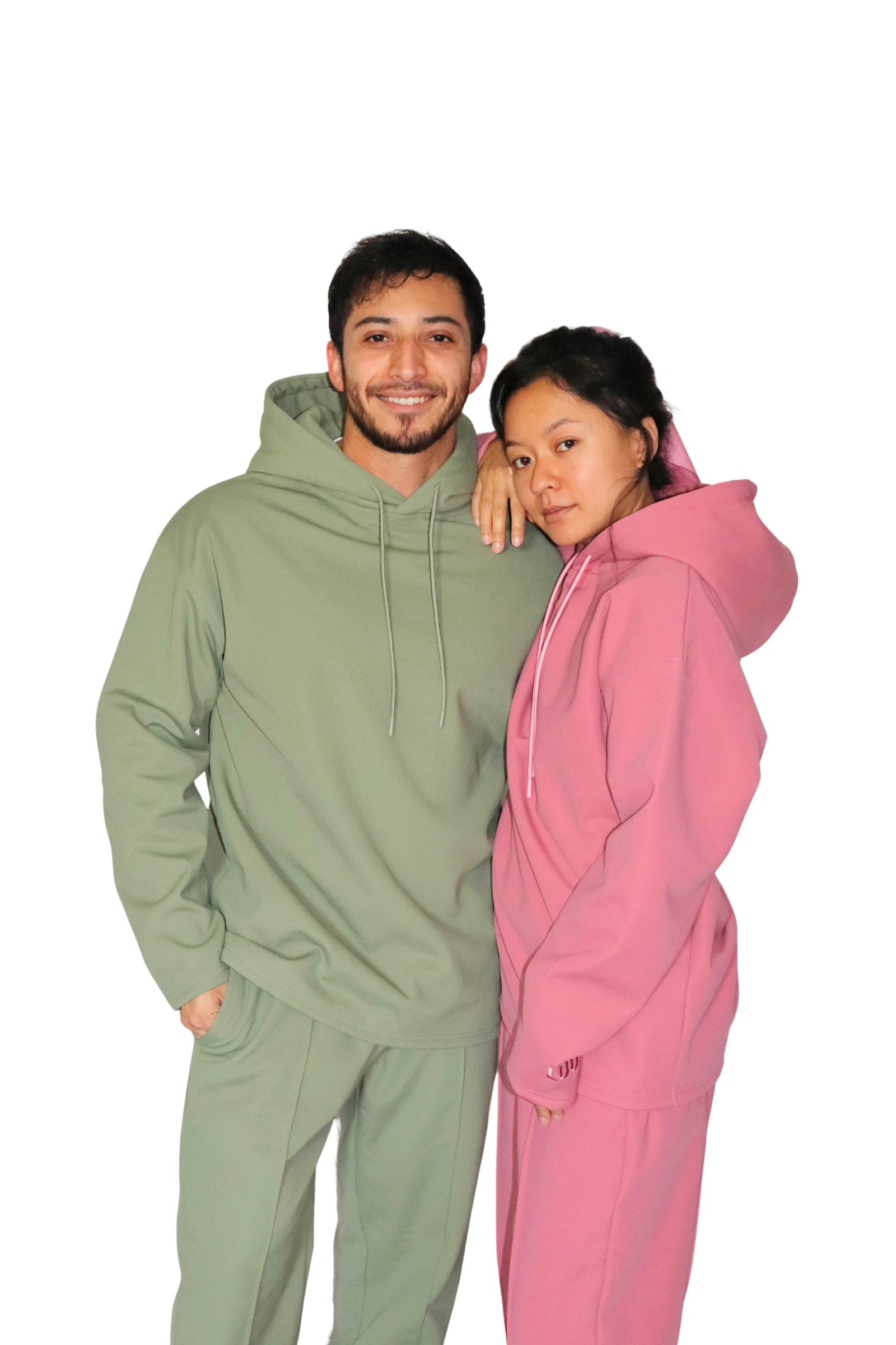 Two people wearing matching green and pink hoodies on a white background