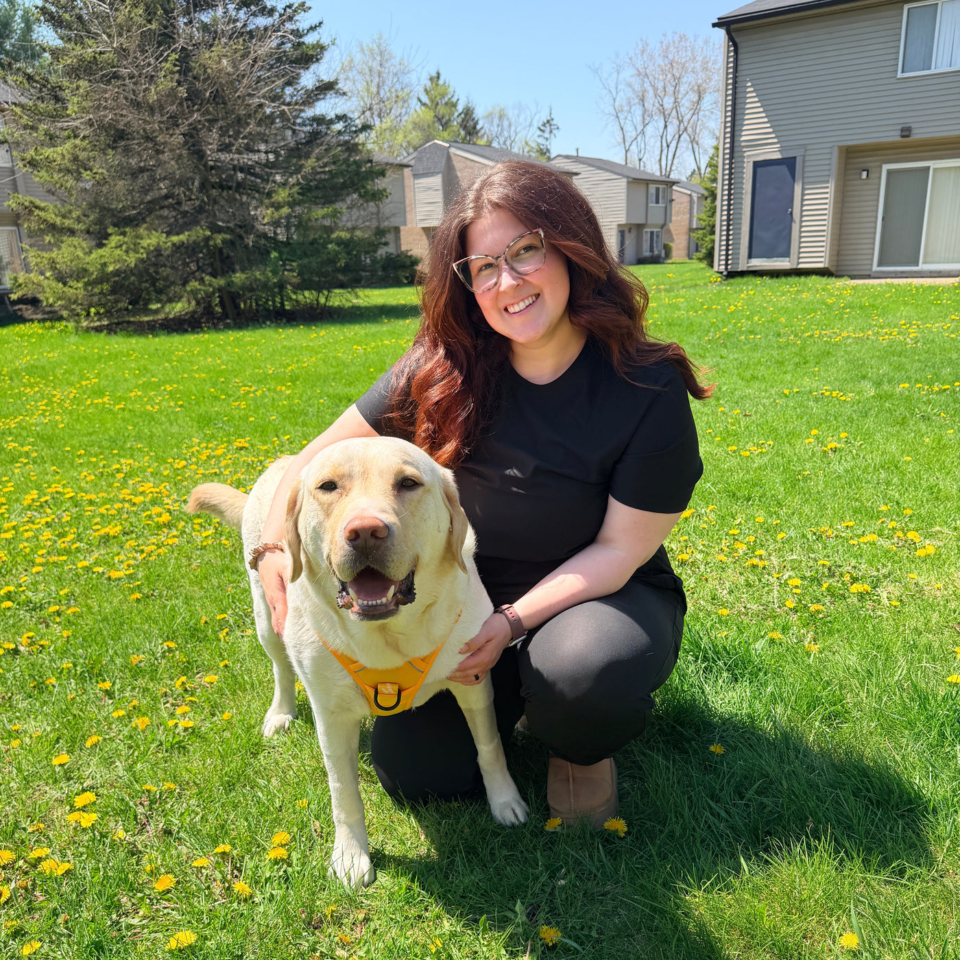 Woman with a dog in a grassy yard with flowers